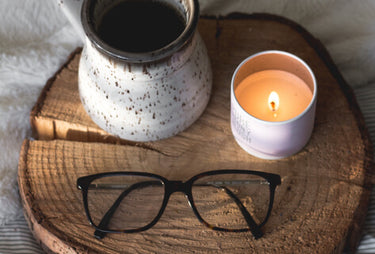 A cup, glasses and candle place on a piece of wood